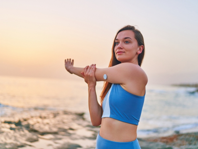 Slim diabetic woman stretching on a beach