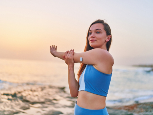 Slim diabetic woman stretching on a beach