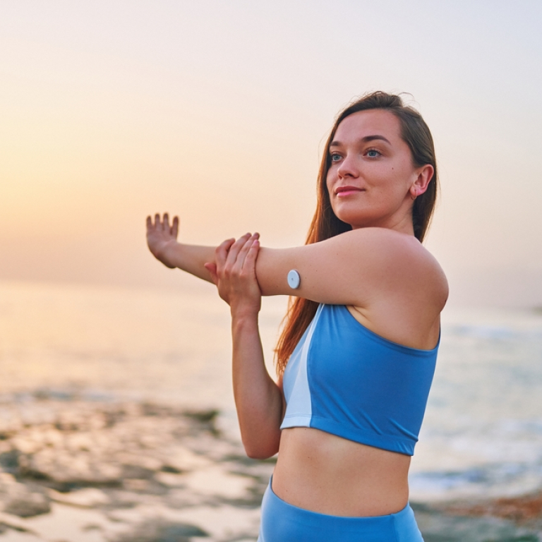 Slim diabetic woman stretching on a beach